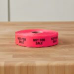 not for sale stickers on a roll of red labels with black print